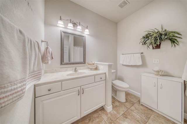 bathroom featuring visible vents, toilet, vanity, and baseboards