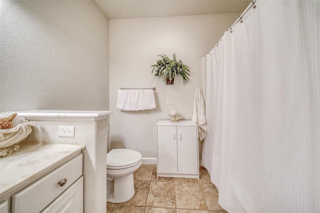 bathroom featuring baseboards, toilet, and vanity