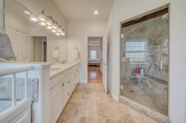 bathroom with double vanity, baseboards, a stall shower, and a sink