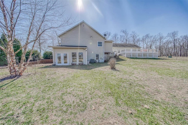 back of property featuring a lawn, central AC unit, and fence