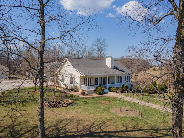 view of front of home with a front lawn, covered porch, roof with shingles, and a chimney