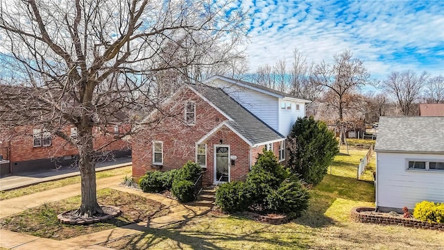 traditional-style home with brick siding, a shingled roof, and a front yard