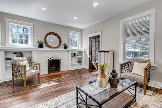 living area with recessed lighting, baseboards, wood finished floors, and a fireplace