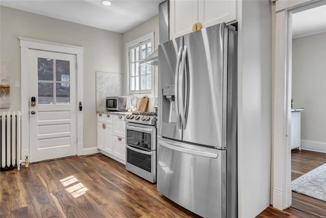 kitchen with stainless steel appliances, dark wood-style floors, radiator heating unit, and white cabinetry