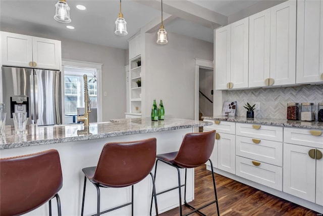 kitchen with a breakfast bar area, dark wood-style flooring, stainless steel refrigerator with ice dispenser, and white cabinetry