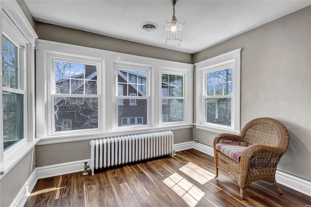 living area with dark wood finished floors, visible vents, radiator heating unit, and baseboards