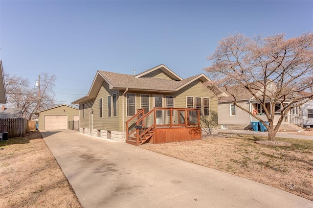 bungalow-style house featuring an outbuilding, fence, a shingled roof, concrete driveway, and a detached garage