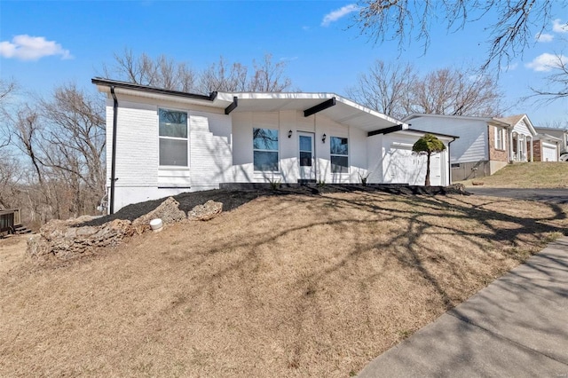 view of front of house featuring brick siding, a front yard, and a garage