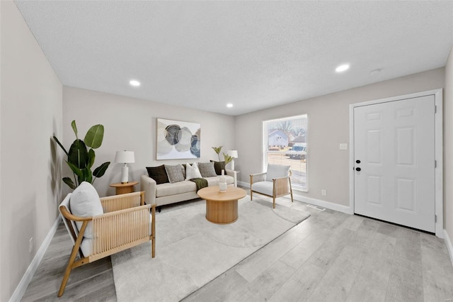 living area featuring recessed lighting, wood finished floors, baseboards, and a textured ceiling