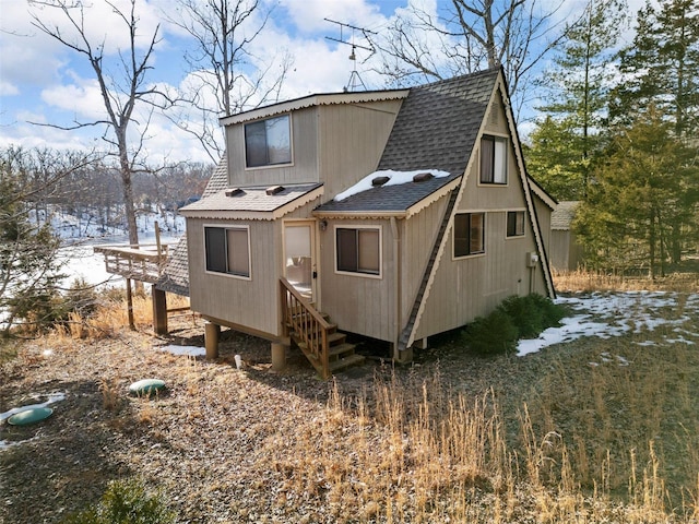 back of house featuring a shingled roof