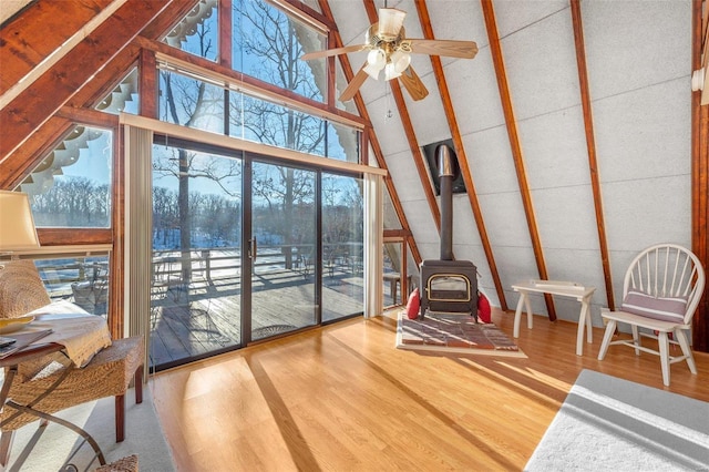 sunroom / solarium featuring a wood stove, plenty of natural light, and a ceiling fan