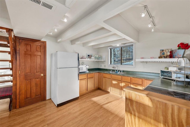 kitchen with dark countertops, light wood finished floors, open shelves, white appliances, and a sink