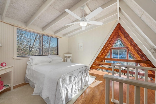 bedroom with a ceiling fan, wood finished floors, and vaulted ceiling with beams