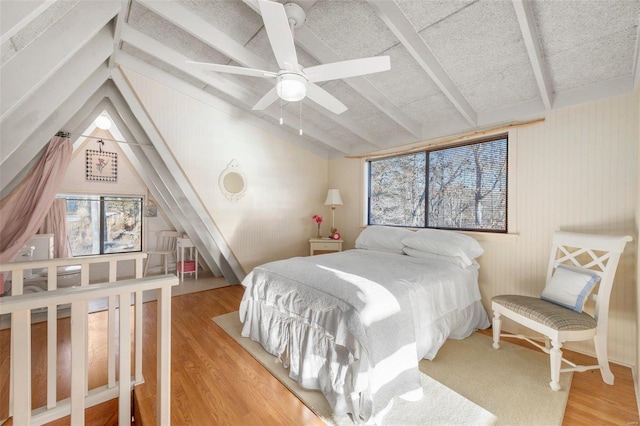 bedroom with vaulted ceiling with beams, a ceiling fan, and wood finished floors