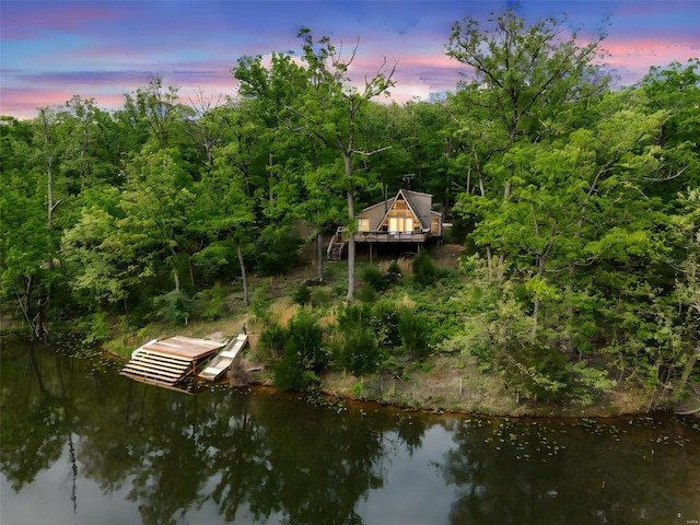 view of dock featuring a view of trees, a deck with water view, and stairway