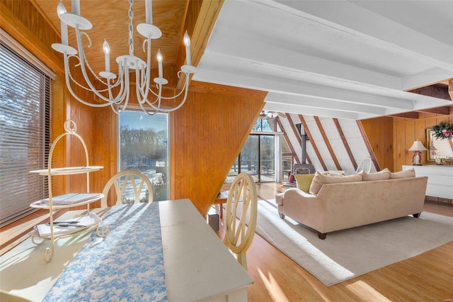 dining area featuring wooden walls, beamed ceiling, wood finished floors, and a notable chandelier