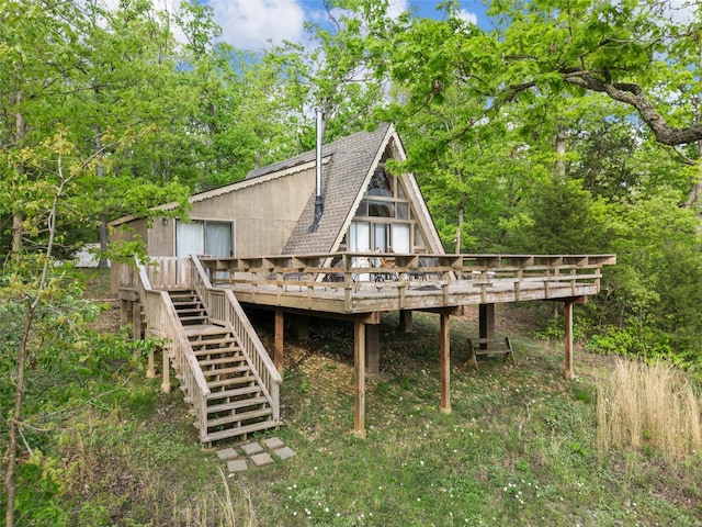 rear view of house featuring roof with shingles, a wooden deck, and stairs