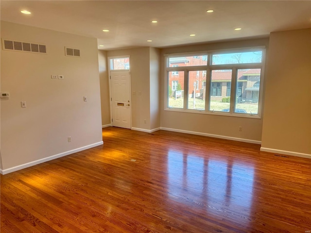 unfurnished living room with visible vents, baseboards, and wood finished floors