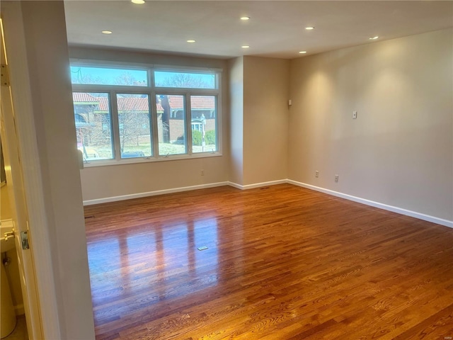 empty room with recessed lighting, wood finished floors, and baseboards