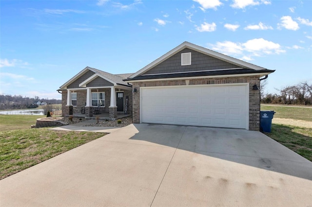 view of front of home featuring an attached garage, concrete driveway, a front lawn, and a water view