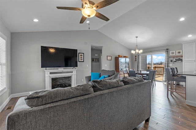 living room with visible vents, lofted ceiling, a fireplace, dark wood-style flooring, and ceiling fan with notable chandelier