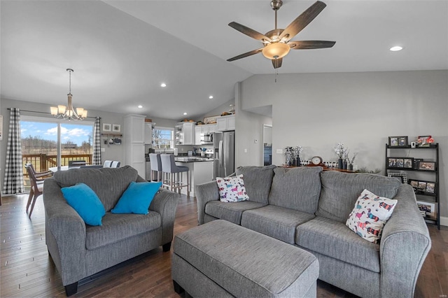 living area featuring dark wood finished floors, vaulted ceiling, plenty of natural light, and ceiling fan with notable chandelier