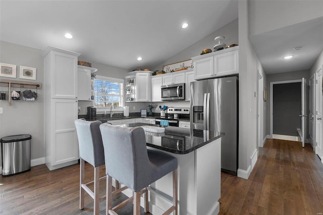 kitchen with dark wood finished floors, a breakfast bar area, stainless steel appliances, white cabinetry, and a sink