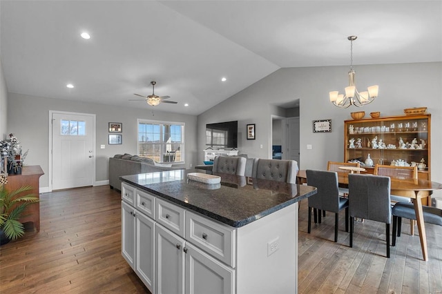 kitchen with a kitchen island, vaulted ceiling, hardwood / wood-style floors, ceiling fan with notable chandelier, and white cabinets