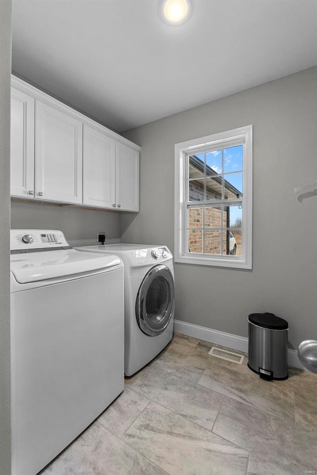 clothes washing area with baseboards, cabinet space, separate washer and dryer, and visible vents