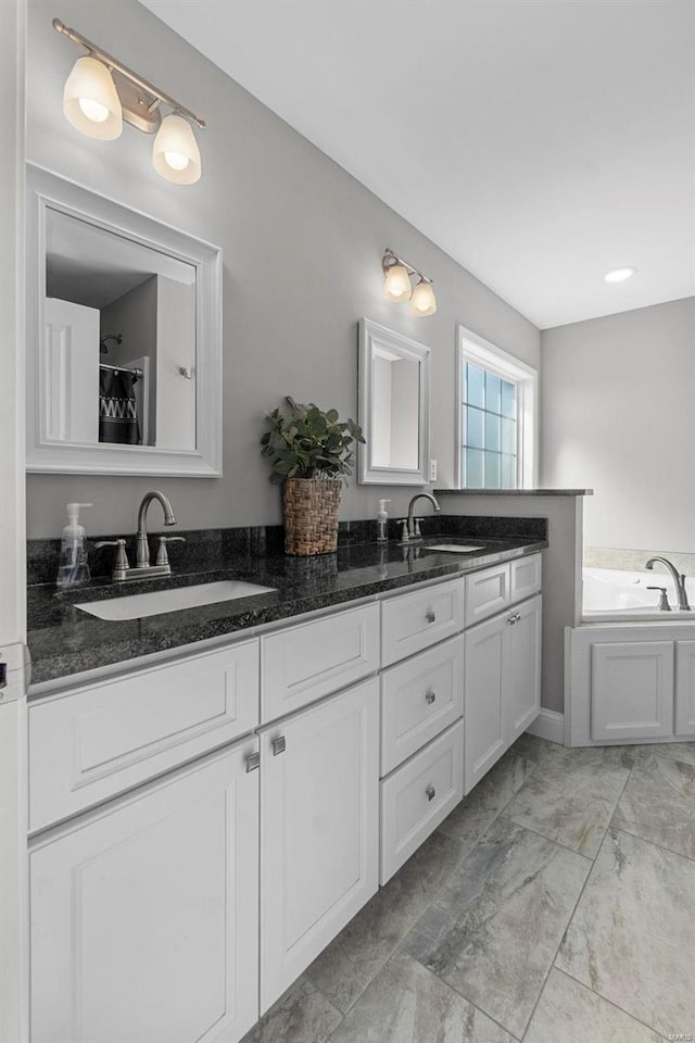 full bathroom featuring double vanity, marble finish floor, a bath, and a sink