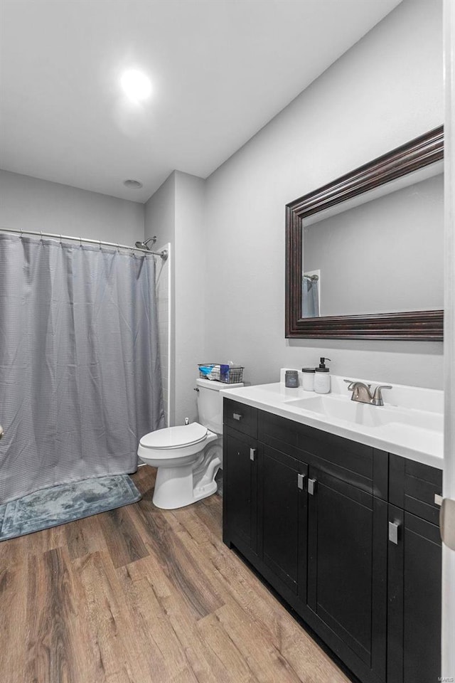 full bath with a shower with shower curtain, toilet, wood finished floors, and vanity