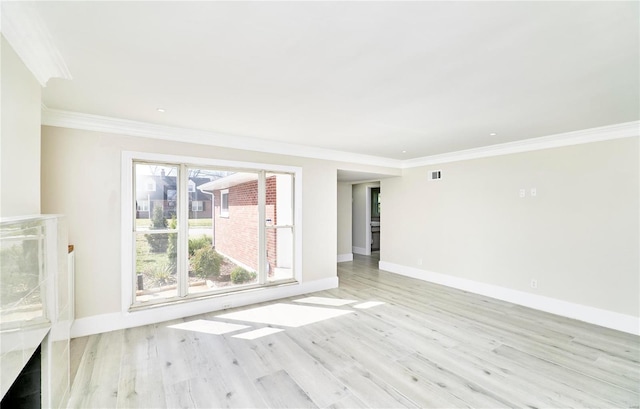 spare room with visible vents, baseboards, crown molding, and light wood finished floors