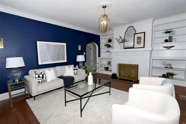 living room with built in shelves, wood finished floors, arched walkways, crown molding, and baseboards