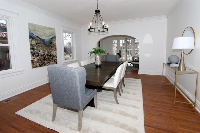 dining space featuring a wealth of natural light, visible vents, arched walkways, and wood finished floors