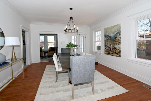 dining area with an inviting chandelier, dark wood-type flooring, crown molding, and visible vents