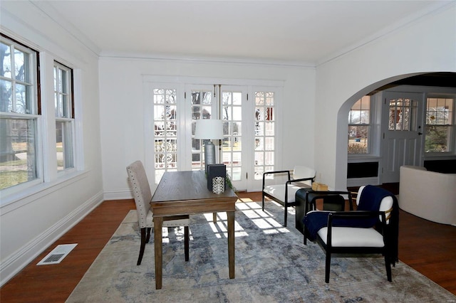 dining area with a wealth of natural light, visible vents, arched walkways, and wood finished floors