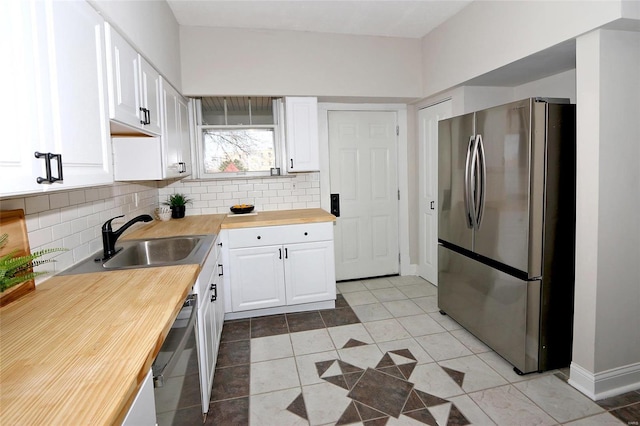 kitchen featuring backsplash, wooden counters, white cabinetry, stainless steel appliances, and a sink