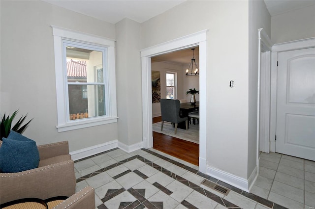 interior space with tile patterned flooring, a notable chandelier, visible vents, and baseboards