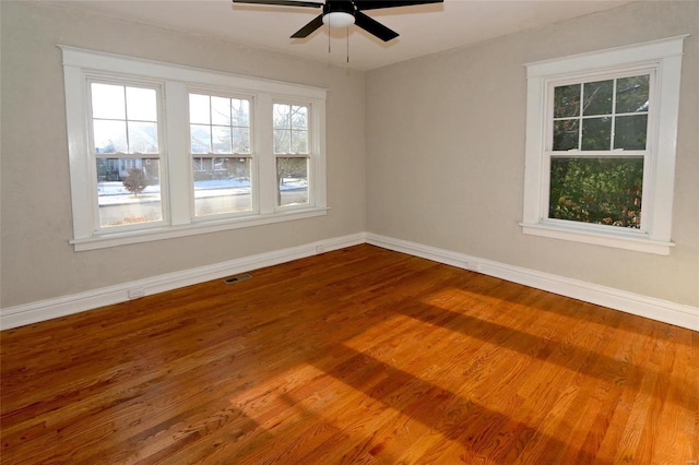 unfurnished room with visible vents, baseboards, wood finished floors, and a ceiling fan