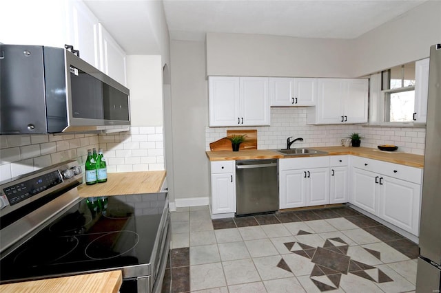 kitchen with a sink, white cabinets, appliances with stainless steel finishes, and butcher block countertops