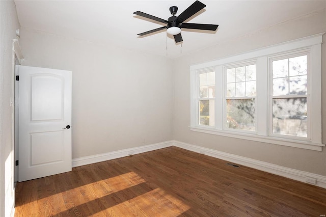 empty room with visible vents, a ceiling fan, baseboards, and wood finished floors