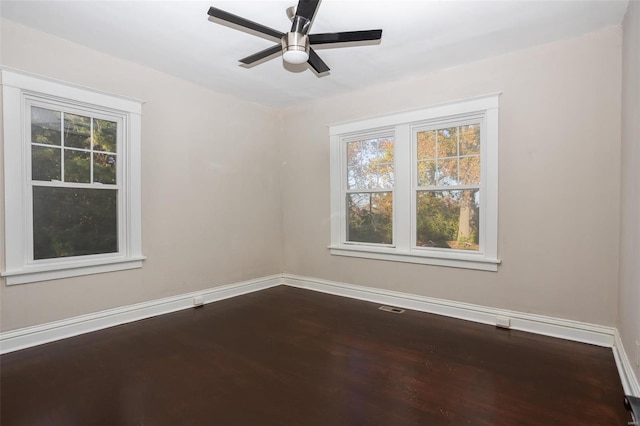 spare room featuring visible vents, baseboards, ceiling fan, and dark wood-style flooring