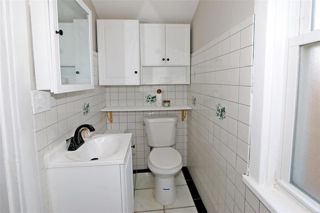 bathroom featuring tile patterned flooring, tile walls, toilet, and vanity