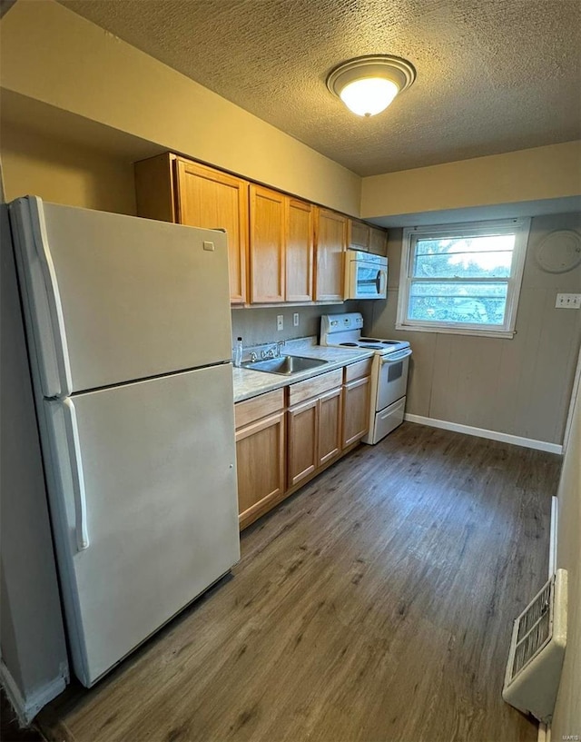 kitchen featuring light countertops, wood finished floors, white appliances, a textured ceiling, and a sink