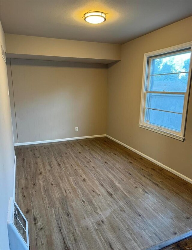 spare room featuring wood finished floors, visible vents, and baseboards