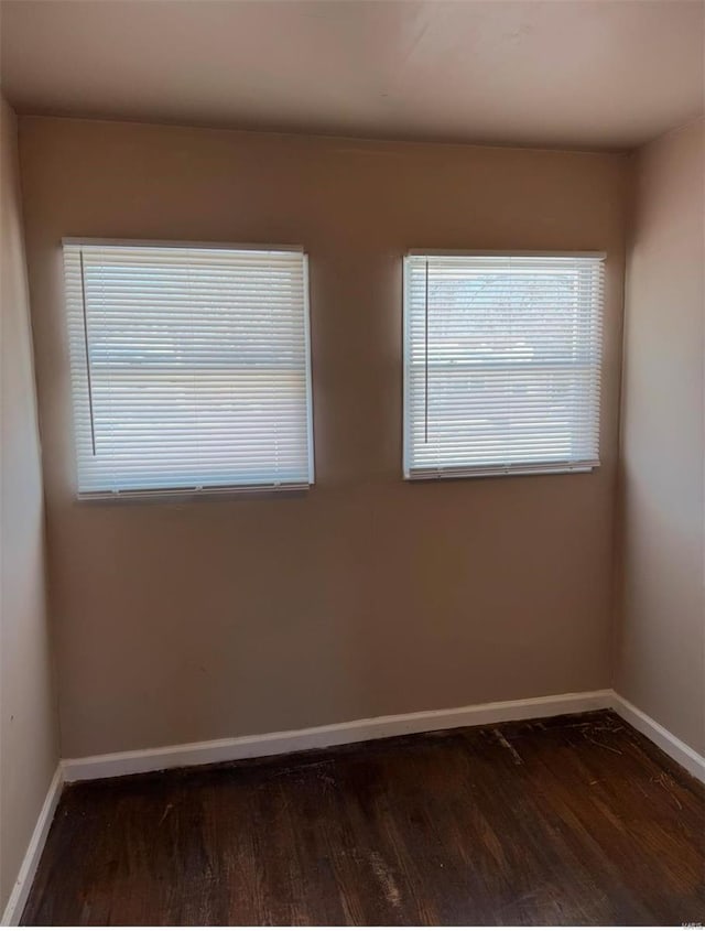 spare room with dark wood-type flooring and baseboards