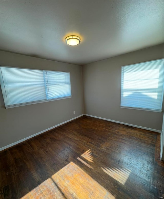 spare room with baseboards and wood finished floors