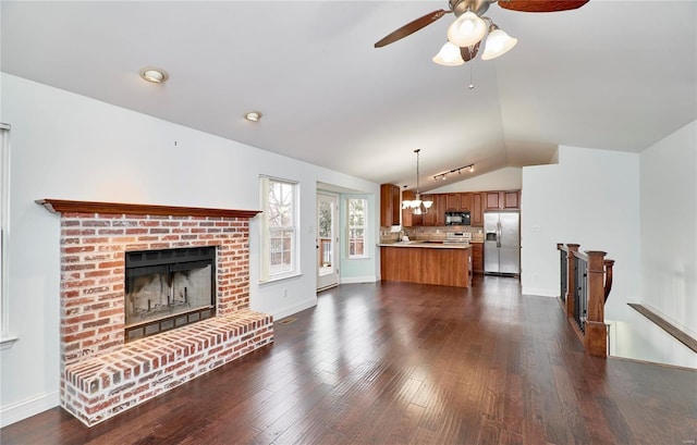 living area with a ceiling fan, baseboards, a brick fireplace, dark wood-style flooring, and vaulted ceiling