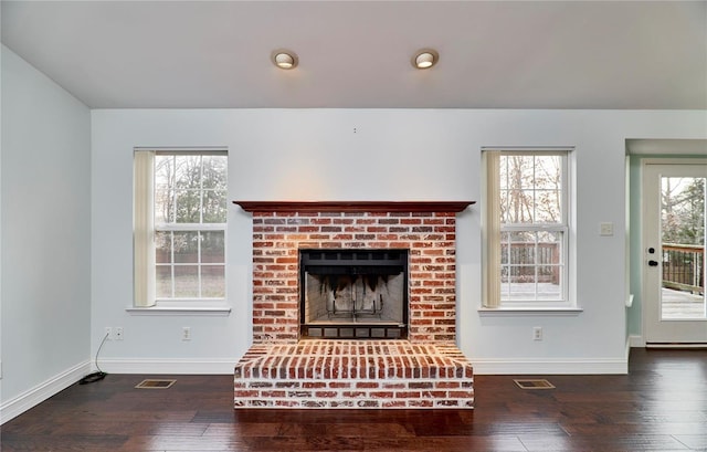 unfurnished living room featuring visible vents, plenty of natural light, and hardwood / wood-style floors