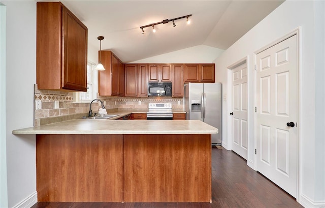 kitchen with brown cabinetry, a peninsula, a sink, light countertops, and appliances with stainless steel finishes